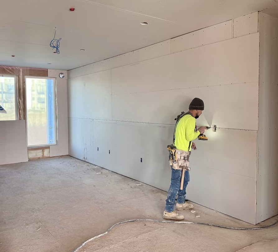 Drywall installation on metal stud framing inside a multifamily unit